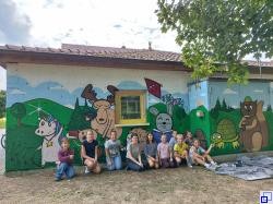Kinder beim Programmpunkt Graffiti vor dem gemalten Bild